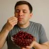 Мужчина ест много черешни