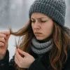 Девушка зимой рассматривает сломанные кончики своих волос