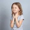 Девочка держит горло, трудно дышать