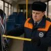 Контролёр в автобусе измеряет ширину лыж рулеткой.