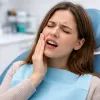 Женщина держится за щёку от боли