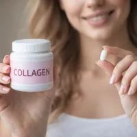 Девушка держит в одной руке банку с коллагеном, а в другой — таблетку