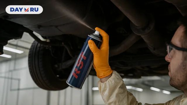 Механик наносит антикоррозийный спрей на автомобиля